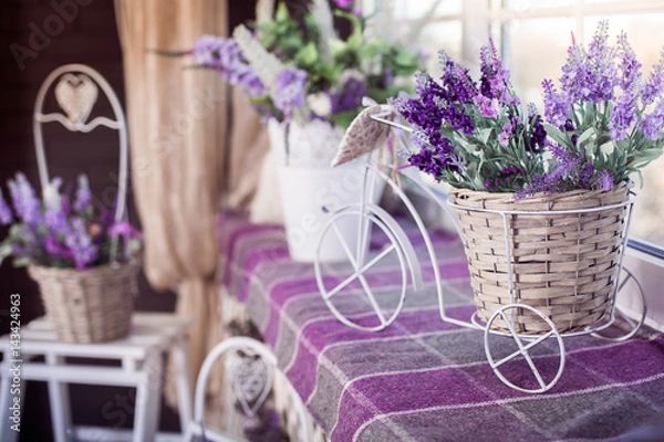 Fototapeta Lavender flowers in small decorative bicycle pot stand on the windowsill. Spring interior design of room. Side view.
