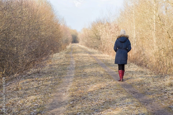 Fototapeta Young woman walking along the trail in the park in sunny spring day.