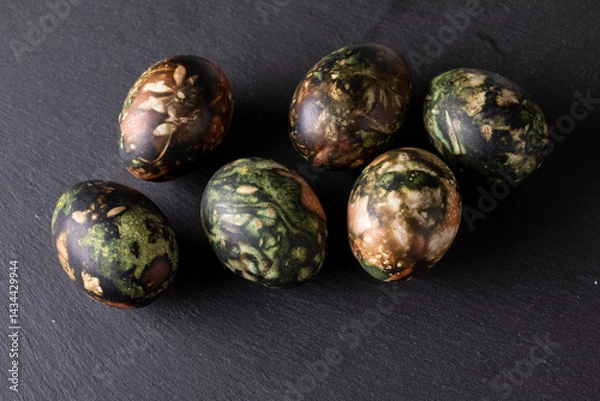 Fototapeta Easter decorations. Traditionally coloured Easter eggs on a black stone background. Top view, copy space.
