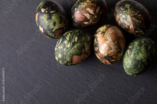 Fototapeta Easter decorations. Traditionally coloured Easter eggs on a black stone background. Top view, copy space.