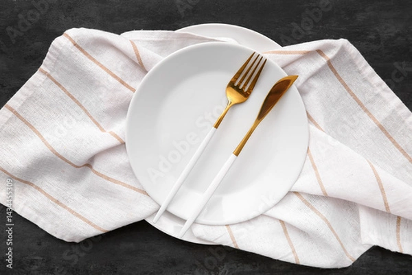 Obraz Plate with cutlery and napkin on black grunge background