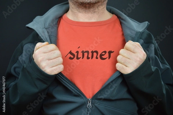 Fototapeta mężczyzna pokazujący swoją koszulkę z napisem SINNER