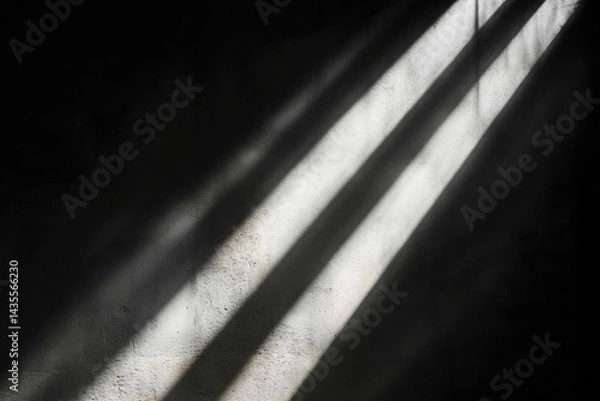 Fototapeta Sunlight streams through a barred window, casting dramatic shadows on a textured wall