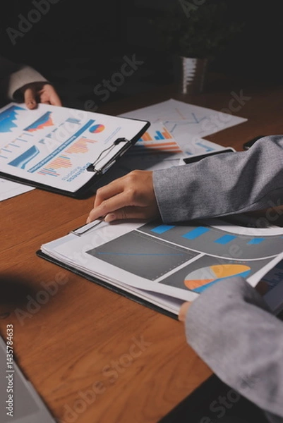 Fototapeta Group of confident business people point to graphs and charts to analyze market data, balance sheet, account, net profit to plan new sales strategies to increase production capacity.