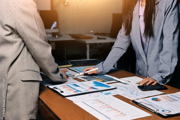 Fototapeta Group of confident business people point to graphs and charts to analyze market data, balance sheet, account, net profit to plan new sales strategies to increase production capacity.