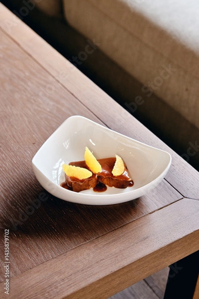 Fototapeta a piece of cheesecake with an orange in a plate on the table