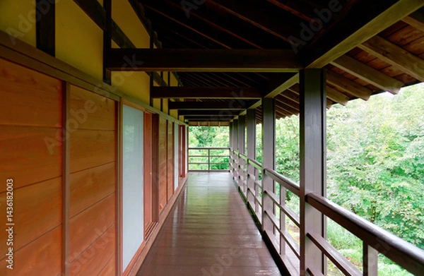 Fototapeta A diminishing perspective of a veranda in a traditional Japanese house with wooden floors, eaves, handrails, sliding doors and lush greenery of trees in the courtyard, in Tokamachi, Niigata, Japan