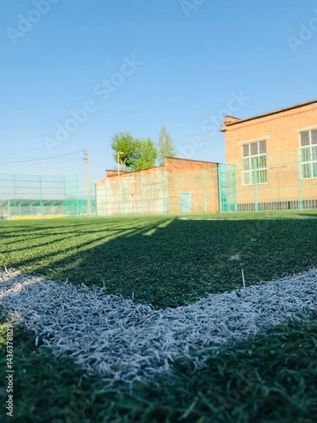 Fototapeta View of a soccer field with artificial turf and bright sky