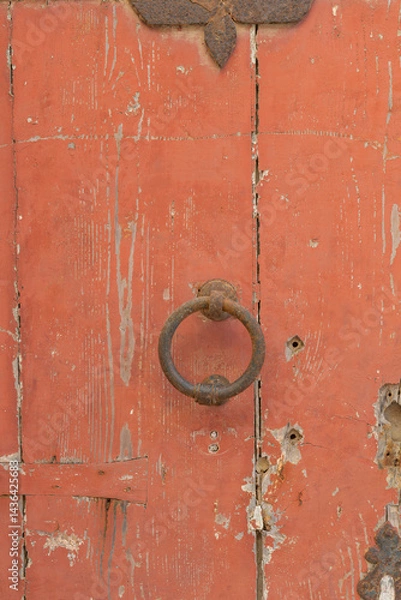 Obraz Old rustic red wooden door with cracked paint and metal ring handle, perfect for use as background, texture, or vintage design projects.