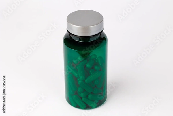 Obraz Green Supplement Bottle Surrounded by White Capsules, Green bottle with a silver cap placed on a white background.