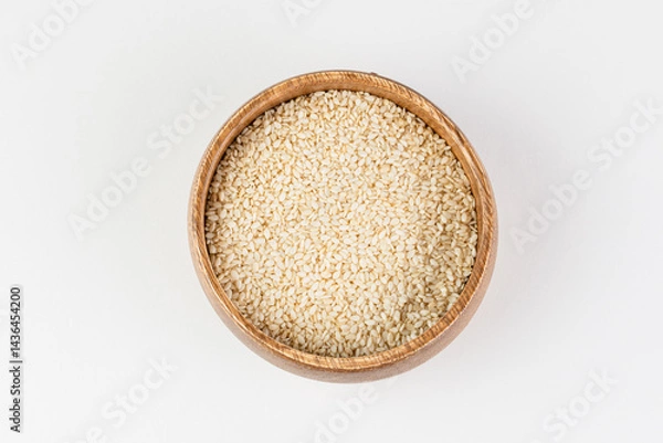 Fototapeta Top view of white sesame seeds in wooden bowl on white background isolated