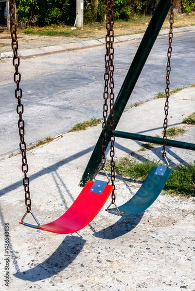 Obraz Empty red and green swings on sunny day in urban playground setting