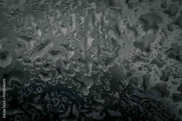 Fototapeta Close-up of water droplets creating abstract, organic patterns on a gray-toned glass surface, providing a moody and textured background with copy space.