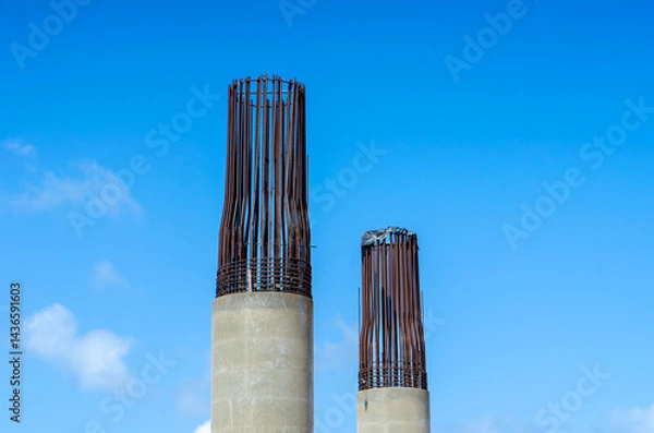 Obraz Concrete Columns with Exposed Rebar under Bright Blue Sky