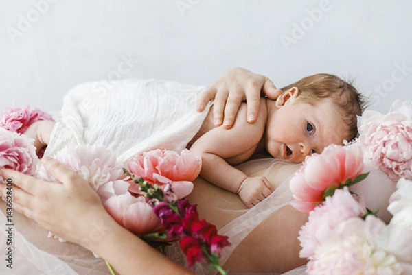 Fototapeta Happy Mothers day. Cute newborn baby lying on mother belly with peony flowers. Love and care concept. Portrait of baby son on mom tummy, tender moment. Adoption and maternity.