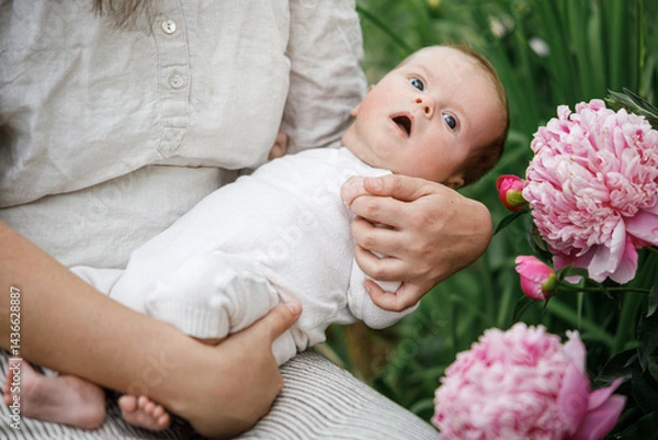 Fototapeta Cute newborn baby in mother hands close up among flowers in the garden. Love, care and family in countryside concept. Happy Mothers day! Adoption and maternity
