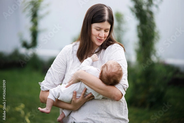 Fototapeta Happy Mothers day! Mother hugging cute newborn baby  in the garden. Love, care and family in countryside concept. Adoption and maternity