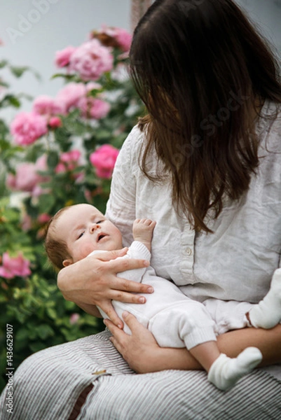 Fototapeta Mother hugging cute newborn baby among flowers in the garden. Love, care and family in countryside concept. Happy Mothers day! Adoption and maternity