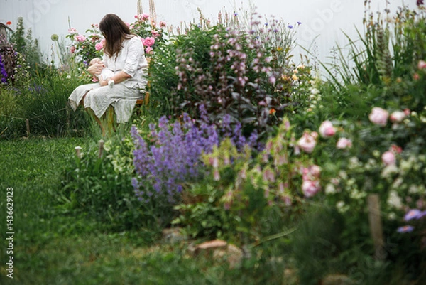 Fototapeta Happy Mothers day! Mother hugging cute newborn baby among flowers in the garden. Love, care and family in countryside concept. Adoption and maternity