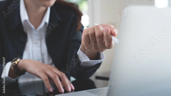 Fototapeta Businesswoman working on laptop computer, online meeting with colleagues via online meeting app, video conference. Business woman in business suit busy working at modern office, close up