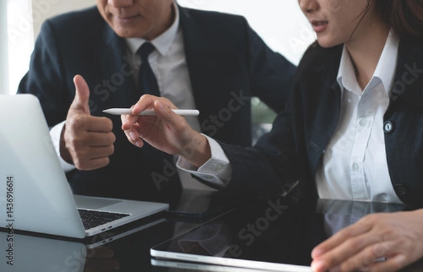 Fototapeta Successful co-working team together working in office. Asian business colleague working on laptop computer and digital tablet, make a discussion on office table, planning. Business teamwork