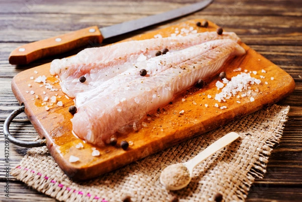 Fototapeta Świeże surowe ryby, filet matkowania z przyprawami, czarny pieprz i sól na drewnianej desce, tło