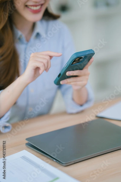 Fototapeta Businesswoman working in office while talking on the phone and taking notes