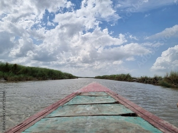 Fototapeta Boat Journey on a River Under a Cloudy Sky