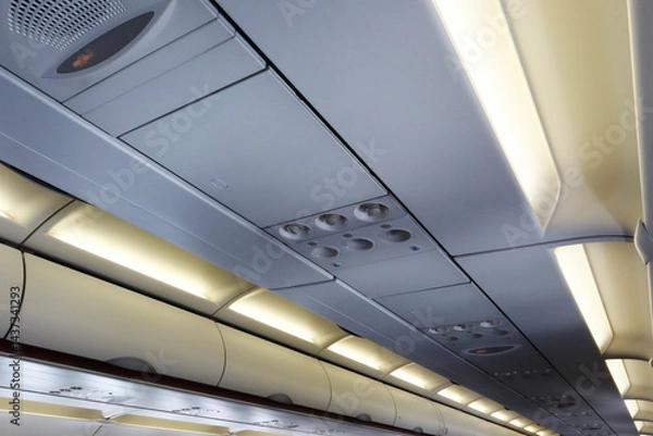 Fototapeta Interior atmosphere of aircraft passenger cabin perspective ceiling show overhead panel, air condition vent and fasten seat belt sign. Image use for airline business presentation background.
