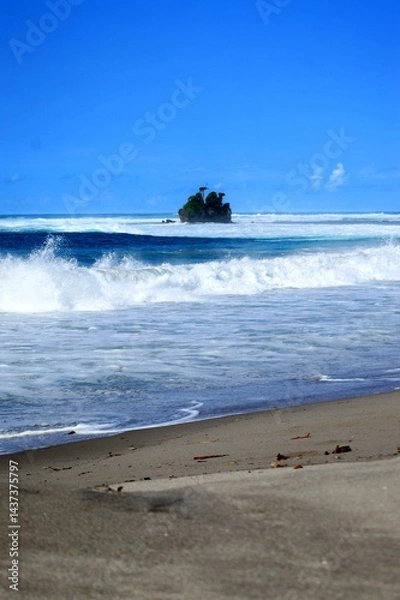 Fototapeta A beautiful sunny day at a tropical beach with waves crashing onto the shore