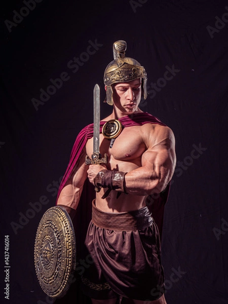 Fototapeta Muscular warrior wearing ancient armor poses with sword and shield