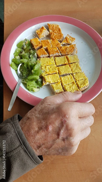 Fototapeta Plate of healthy food in a retirement home. Toast with two kinds of spread, chopped kiwi