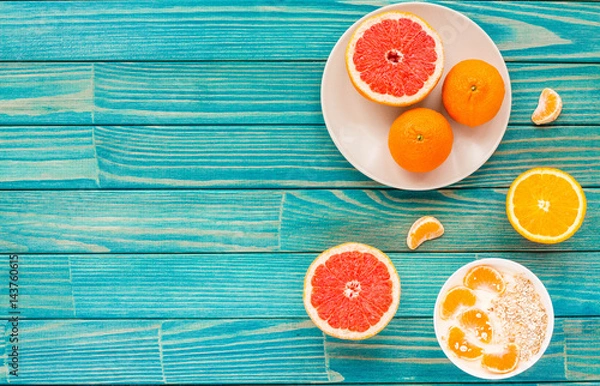 Fototapeta Healthy breakfast with yogurt, colorful fresh citrus fruit, cereal and muesli on turquoise wooden background. Flat lay, top view, mock up.