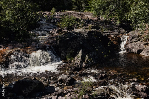 Fototapeta Norwegian mountain river with waterfalls where rapid water flows, creating white foam.