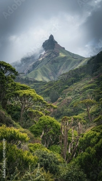 Fototapeta Dramatic misty volcanic peak rising over lush valley with distant hikers below