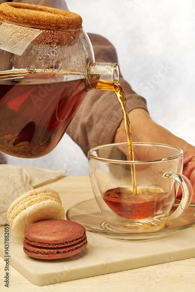 Obraz Pouring a delightful cup of tea paired with elegant macarons for a perfect afternoon break