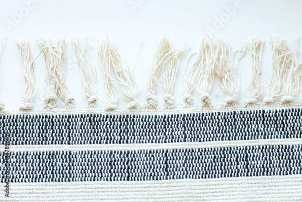 Obraz Detailed shot of woven fabric with textured fringe, showcasing craftsmanship and textile design against a white background.