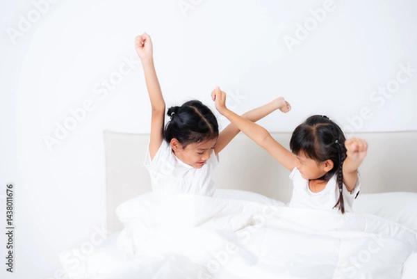 Fototapeta Two cute asian children waking up and stretching in bed