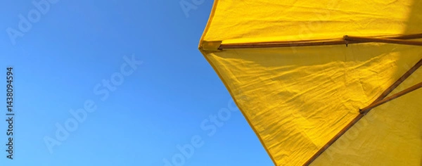 Fototapeta A beach umbrella is an indispensable accessory for a comfortable stay on the beach, protecting from direct sunlight and creating a cozy shade on the beach by the sea in hot weather.