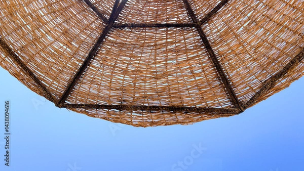 Fototapeta A beach umbrella is an indispensable accessory for a comfortable stay on the beach, protecting from direct sunlight and creating a cozy shade on the beach by the sea in hot weather.