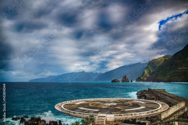 Obraz Helipad located in Porto Moniz, North of Madeira Island. In the background there are blue ocean waves, black rocks and green hills of the coastal line.
