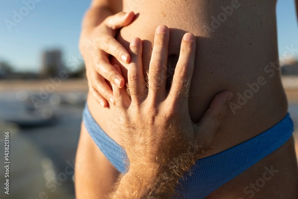 Obraz A boy's hand touches the belly of a girl who is a few months pregnant, in the evening light, Mediterranean, Spain