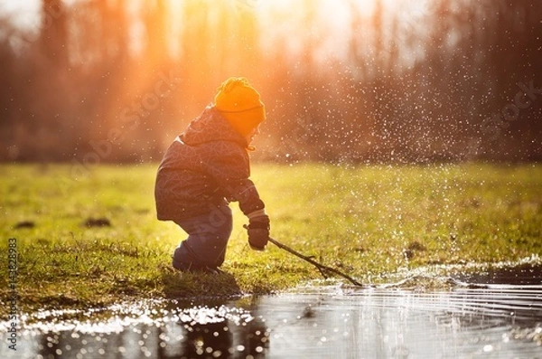 Obraz Little boy playing in puddle at springtime