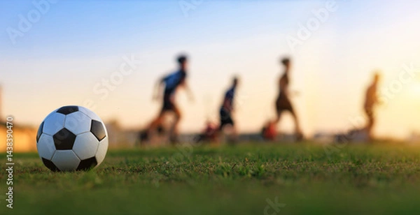Fototapeta Action sport outdoors of kids having fun playing soccer football for exercise in community rural area under the twilight sunset sky.