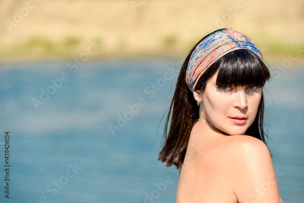 Fototapeta Portrait of a beautiful sexy brunette girl with bare shoulders on the beach in sunny weather