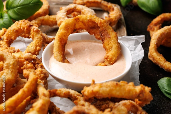 Obraz Deep fried onion rings on wooden board with sauce