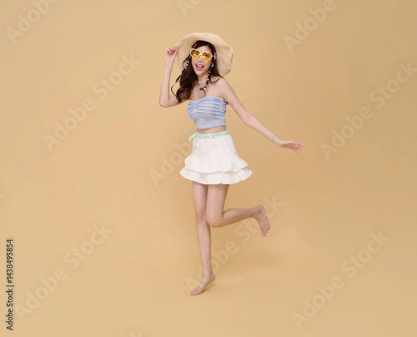Obraz Happy Young beautiful Asian woman dressed in summer clothes smiling jumping to travel isolated on nude color background.
