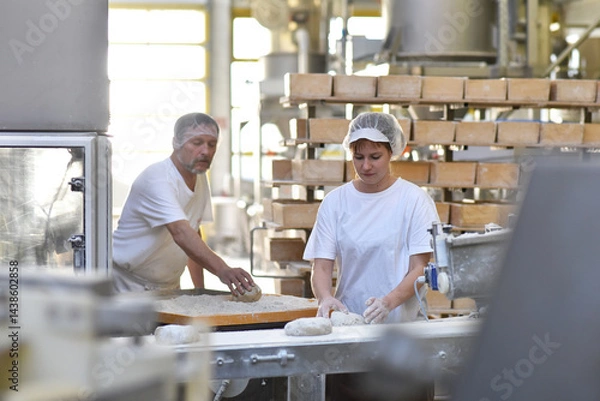 Obraz Worker in a large bakery - industrial production of bakery products on an assembly line