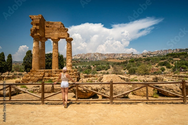 Fototapeta A woman exploring the Valley of the Temples (Valle dei Templi), Temple of Castor and Pollux one of the greeks temple of Italy, Agrigento, Sicily. Temple of Concordia, Agrigento, Sicily, Italy. 