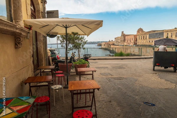 Obraz Syracusa Bay, Sicily, Italy. Travel and sightseeing journey concept. Small restaurant tables with umbrela. Streed food concept